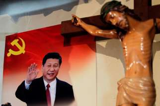 A poster of Chinese President Xi Jinping hangs next to a crucifix on the wall of the house of a Tibetan Catholic on Christmas Eve in Niuren village, in China&#039;s Yunnan province, in this Dec. 24, 2018, file photo. 