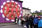 People pause near a mural showing the 14 victims of 1972’s Bloody Sunday during a memorial service to mark the 50th anniversary of the tragedy in Derry, Northern Ireland, Jan. 30. The head of the Irish bishops’ conference has noted that no one from the British army has ever been prosecuted for the killings.