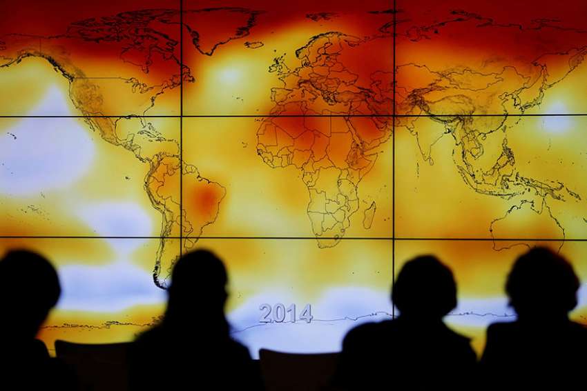 Participants look at a screen showing a world map with climate anomalies during the World Climate Change Conference at Le Bourge, France, in this Dec. 8, 2015, file photo.