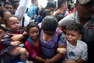  Children cry next to their mother after a caravan of Honduran migrants trying to reach the U.S. stormed a border checkpoint Oct. 19 in Ciudad Hidalgo, Mexico. 
