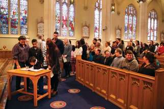 Catechumens and their sponsors line up to sign the book at the Rite of Election during the First Sunday of Lent at the Cathedral Basilica of Christ the King in Hamilton.