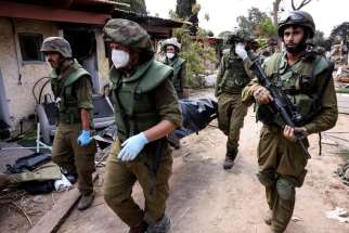 Israeli soldiers carry a body in Kfar Aza, a kibbutz in southern Israel, Oct. 10. IDF works to remove the bodies of the victims from the homes where they were murdered by Hamas terrorist infiltrators Oct. 7.