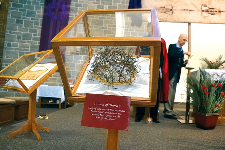 The replica of the Crown of Thorns shows a cap of Palestinian thorns that would have created wounds consistent with those on the Shroud. In the background, the Shroud replica hangs over the altar.