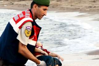 A member of the Turkish military carries a young migrant Sept. 2, who drowned in a failed attempt to sail to the Greek island of Kos, in the coastal town of Bodrum, Turkey. A Turkish media report says at least 11 migrants have died and five others are missing after boats carrying them to the Greek island of Kos capsized.