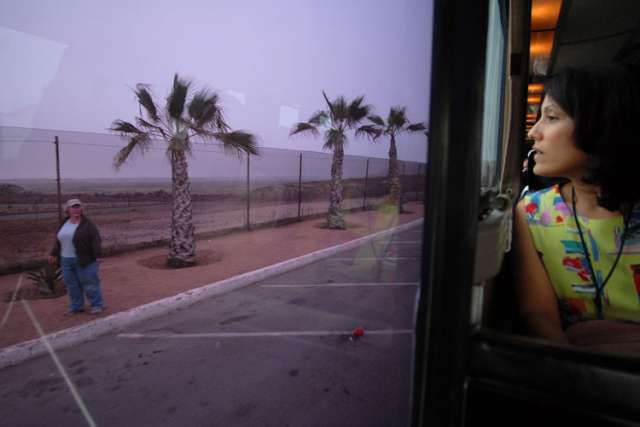 Yelda Cortez of the U.S. bishops&#039; Migration and Refugee Services office, looks out the window of a bus as it makes its way along the U.S.-Mexico border fence.