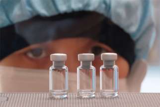 A scientist checks quality control of COVID-19 vaccine vials for correct volume at the Clinical Biomanufacturing Facility in Oxford, England, April 2, 2020.