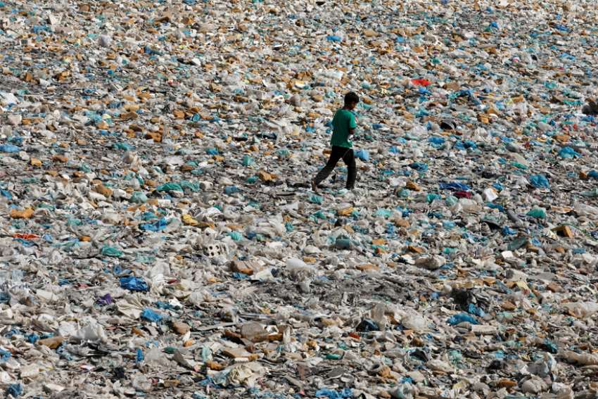 A boy walks over a drainage channel littered with garbage in Karachi, Pakistan, on Earth Day April 22, 2020.