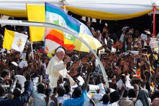 The Vatican flag and a peace banner are seen as Pope Francis greets the crowd as he arrives for a meeting with young people at the Kololo airstrip in Kampala, Uganda Nov. 28.