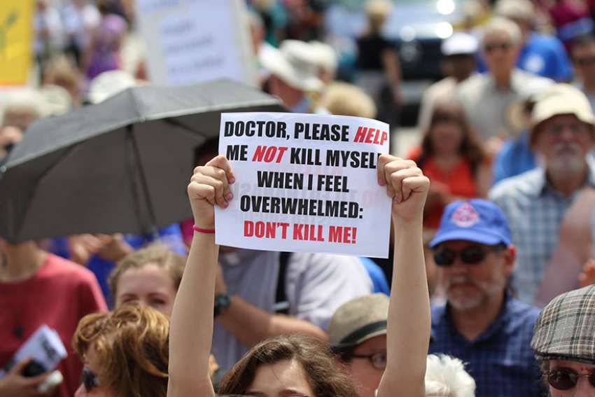A woman holds up a sign during a rally against assisted suicide on Parliament Hill in Ottawa in 2016. 