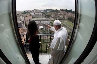 Pope Francis waves from a balcony alongside Rome Mayor Virginia Raggi during a visit to City Hall March 26, 2019. 