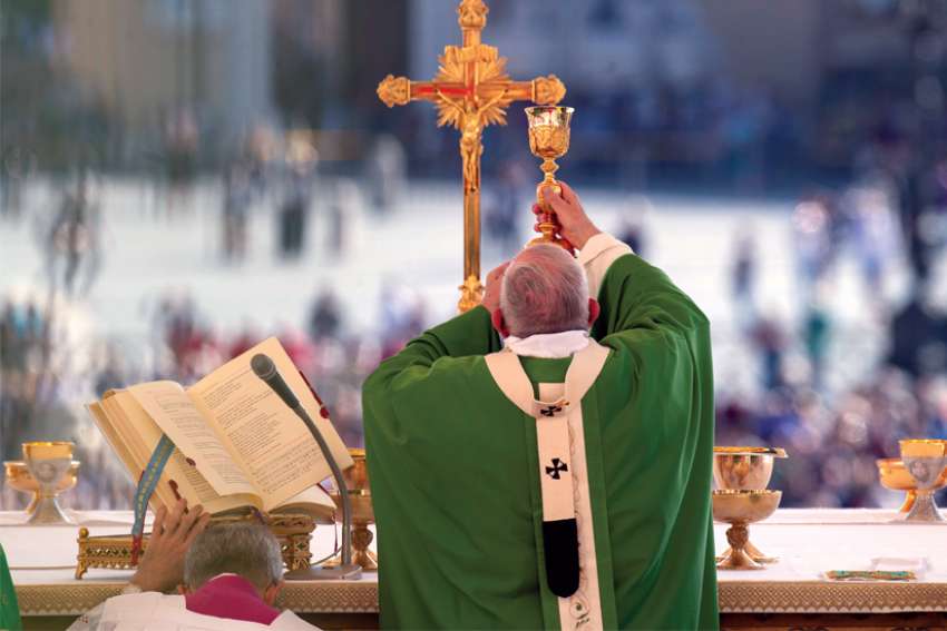 Pope Francis elevates the Eucharist as he celebrates the Mass at the Vatican.