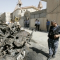 A police officer inspects a burned vehicle after a bomb attack outside Holy Family Syrian Catholic Church in central Kirkuk, Iraq, north of Baghdad, Aug. 2.