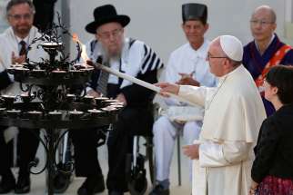 Pope Francis lights a candle during an interfaith peace gathering outside the Basilica of St. Francis in Assisi, Italy, Sept. 20. The pope and other religious leaders were attending a peace gathering marking the 30th anniversary of the first peace encounter.