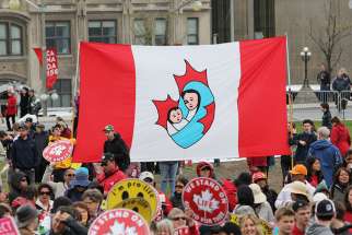 Pro-lifers hold up a modified Canadian flag with Mary and infant Jesus placed in the maple leaf at the 2017 March For Life in Ottawa. 