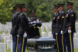 An officer with the U.S. Army military honor guard holds the U.S. flag over the casket of the late Carl Mann Sr., a World War II veteran, during his burial June 6, 2019, at Arlington National Cemetery in Virginia, outside Washington. In a joint appeal marking 80 years since start of World War II, Polish and German bishops warn that Europeans still need to work toward peace and unity.
