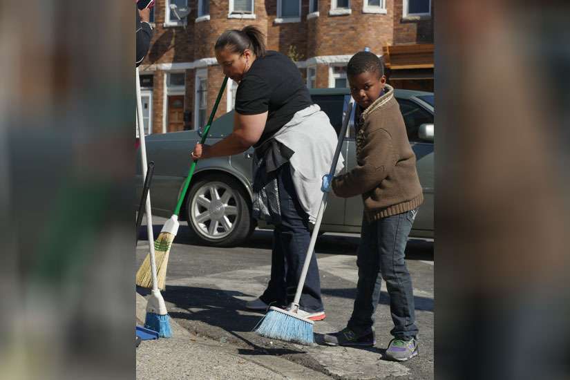 Christy Lewis and a neighborhood youth sweep broken glass and debris outside a looted store in West Baltimore April 28. Maryland Gov. Larry Hogan declared a state of emergency and activated the National Guard to address the violence that erupted in respo nse to the unexplained death of a 25-year-old black man while in police custody.