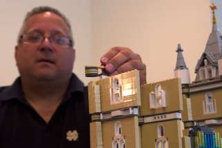 Fr. Bob Simon, pastor of St. Catherine of Siena parish in Moscow, Pa., places a Lego piece on a model church he is building in a spare room in his rectory Oct. 24. Simon says his Lego-building hobby has served as an evangelization tool. 