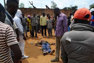  Civilians gather around the body of a man June 22 killed during fighting between the army and militia fighters in Beni, Congo. Catholic bishops in Congo accused their government of suppressing civil liberties and demanded free elections envisaged under a church-brokered New Year accord. 