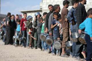 Internally displaced Syrians wait in line for food April 15 at a camp outside Damascus. The United States, France and Britain launched airstrikes in Syria to punish President Bashar Assad for an apparent chemical attack.