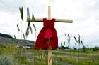 A child&#039;s red dress hangs on a cross near the grounds of the former Kamloops Indian Residential School in Kamloops, British Columbia, June 6, 2021.