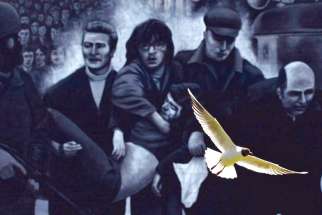 A seagull flies in front of a mural which shows a group of men, led by then-Fr. Edward Daly, right, carrying the body of shooting victim Jackie Duddy during 1972’s Bloody Sunday in Derry, Northern Ireland, one of the most infamous days in Northern Ireland’s “The Troubles.”