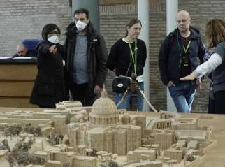 People wearing masks for protection from the coronavirus look at a model of the Vatican at the Vatican Museums. The Vatican announced March 8 that the Vatican Museums will be closed until April 3 as a precaution against spread of the coronavirus.