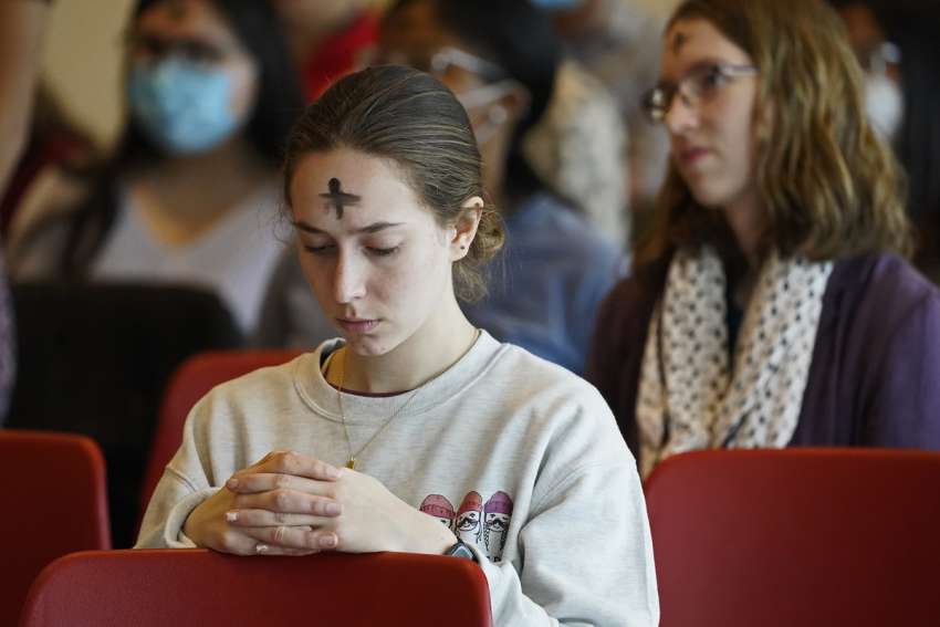 A student prays during an Ash Wednesday Mass March 2, 2022, at Stony Brook University in Stony Brook, N.Y.