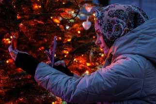 A woman takes a photo of decorations on a Christmas tree in front of the St. Sophia Cathedral in Kyiv, Ukraine, Dec. 6, 2023, amid Russia&#039;s ongoing war on the East European country.
