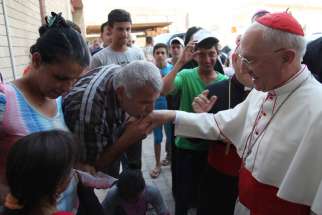 A man kisses the ring of Cardinal Fernando Filoni during an Aug. 13 visit to Irbil, Iraq. Pope Francis met Cardinal Filoni Aug. 21, the morning after the cardinal returned to the Vatican following the Aug. 13-20 visit to Iraq as the pope&#039;s envoy to bes ieged minorities.