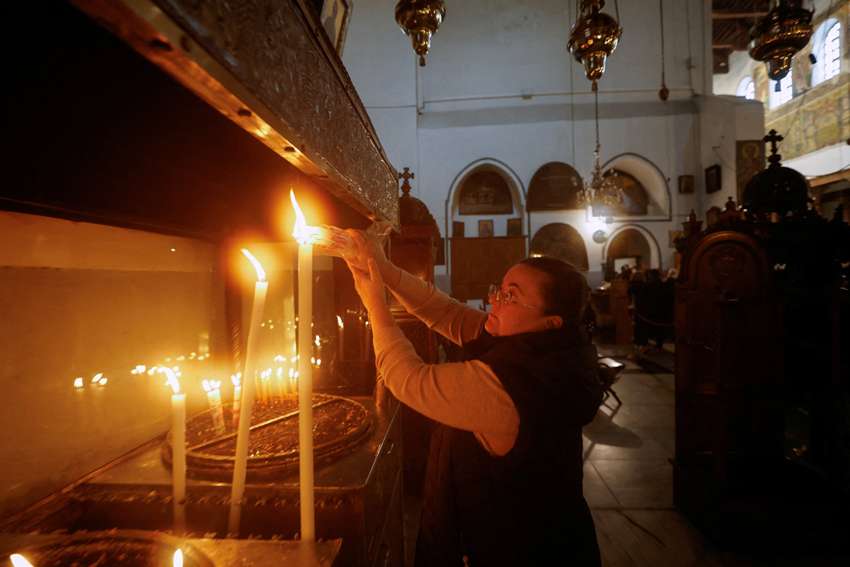 A woman lights candles ahead of a ceremony to launch the beginning of the Christmas season at the Church of the Nativity in Bethlehem, West Bank, Nov. 26, 2022. In their Christmas message, the patriarchs and heads of churches of the Holy Land compared the suffering of refugees to the suffering of the Holy Family.
