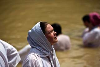 A Christian pilgrim prays as she dips in the water at the baptismal site known as Qasr el-Yahud on the banks of the Jordan River near the West Bank city of Jericho.