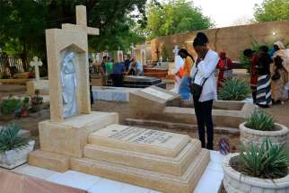 A family prays next to a relative&#039;s grave in a cemetery during All Souls&#039; Day in Khartoum, Sudan, in this Nov. 11, 2014, file photo. With the continuing pandemic, the Vatican has again extended throughout all of November the opportunity to receive a plenary indulgence for visiting a cemetery to pray for the dead.