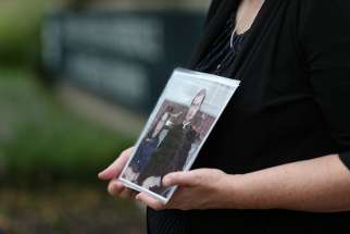 Becky Ianni, who is the Washington and Virginia director of the Survivors Network of those Abused by Priests, or SNAP, holds a photo of herself as a child with a priest Aug. 21 outside the headquarters of U.S. Conference of Catholic Bishops in Washington. Lanni was allegedly abused by the priest in the photo.