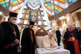 Pope Francis signs a book with a message for Syriac Catholics at the Cathedral of Our Lady of Deliverance in Baghdad March 5, 2021. Also pictured, from left: Syriac Catholic Patriarch Ignace Joseph III Younan, Syriac Catholic Archbishop Ephrem Yousif Mansoor Abba of Baghdad and Chaldean Patriarch Louis Sako of Baghdad.