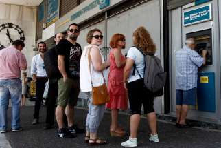People queue to withdraw money from an ATM outside a branch of Greece&#039;s National Bank in Athens, Greece, July 6. 