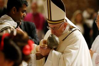  Pope Francis kisses a figurine of the baby Jesus as he visits the Nativity scene at the conclusion of Christmas Eve Mass in St. Peter&#039;s Basilica at the Vatican Dec. 24.