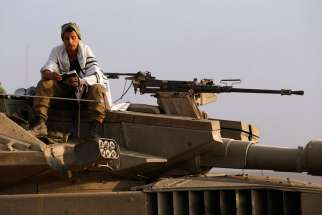 An Israeli soldier prays atop a tank near the border with the Gaza Strip July 23. Israeli forces pounded the Gaza Strip July 23 and said they were meeting stiff resistance from Hamas militants.