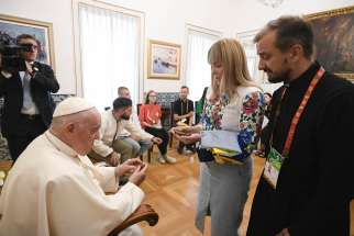A young woman and a priest from Ukraine give Pope Francis shards from their war-torn country during a private meeting Aug. 3, 2023, at the Vatican nunciature in Lisbon, Portugal. The Vatican said the pope spent half an hour with a group of Ukrainian pilgrims attending World Youth Day, listening to their stories and praying for peace.