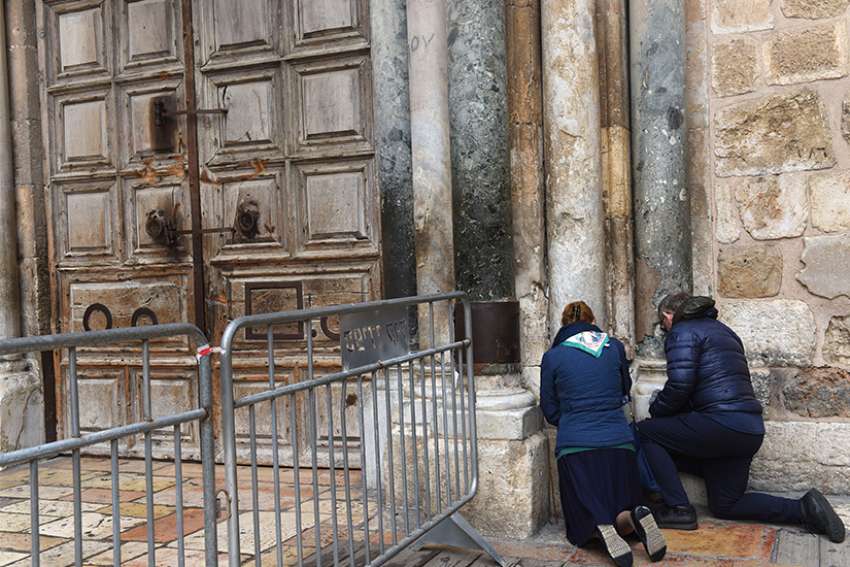 Tourists pray outside the locked doors of the Church of the Holy Sepulchre Feb. 26 in Jerusalem&#039;s Old City. Protesting several recent actions they described as a &quot;systematic campaign against the churches and the Christian community in the Holy Land,&quot; the heads of Christian churches announced Feb. 25 they were closing of the doors of the church. 