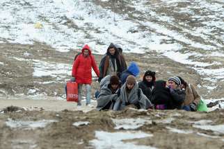 A group of migrants from Syria, Iraq and Afghanistan, on their way to seek asylum in Germany or Austria, walk Jan. 24 along the frozen route from the border between Serbia and Macedonia to a temporary camp for migrants Jan. 2016. 