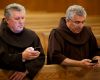 Franciscan Brothers Richard Mcfeely and Robert Frazzetta read prayer requests on their mobile phones Jan. 3 at St. Anthony Friary in Butler, N.J. The largest group of Franciscan friars in the United States is offering the faithful a new way to pray in th e digital age by accepting prayer requests via text messages.