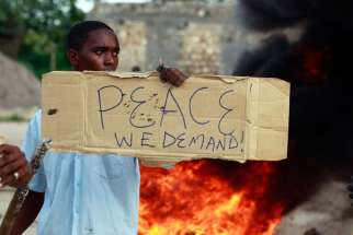 A resident holds a placard as he participates in a June 17 protest against the recent attack by unidentified gunmen in the town of Mpeketoni, Kenya. Nearly 50 people were killed and others wounded when more than two dozen unidentified gunmen attacked the coastal town.