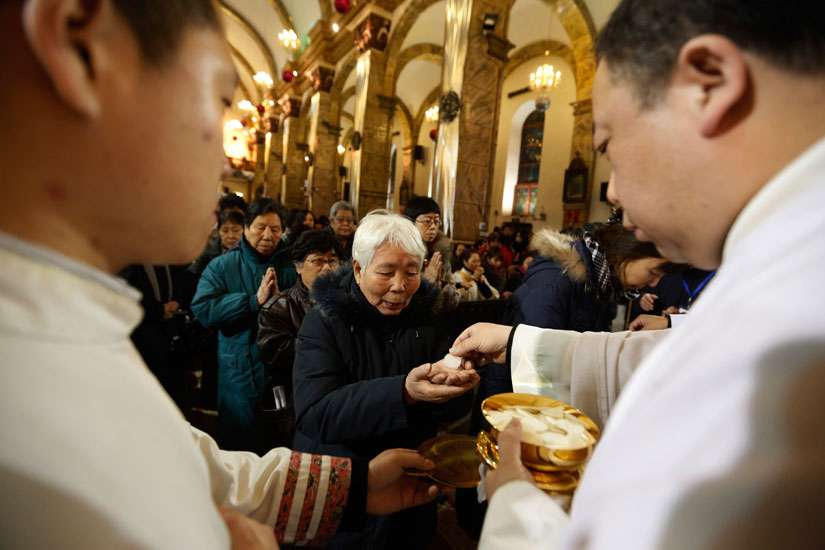 Chinese Catholics receive Communion in 2012 during Christmas Eve Mass in Beijing. A top Politburo official told faith leaders that religious groups must promote Chinese culture and become more compatible with socialism.