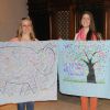 Barbara Gajda, left and Janelle de Rocquigny stand with solidarity banners before departing for Rio de Janeiro. The banner on the left was signed by D&amp;P Manitoba members at St. Ignatius parish and St. Boniface Cathedral and the banner on the right was painted by the youth of St. Boniface Cathedral.