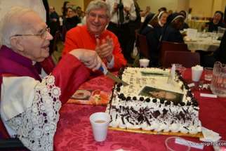 Msgr. Vincent Foy cuts the cake for his 100th birthday celebration with Cardinal Thomas Collins sharing the moment. Msgr. Foy died at the age of 101 March 13.