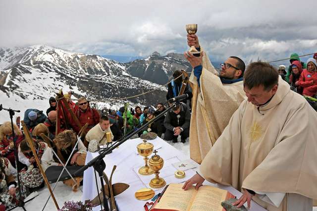 A priest raises the chalice as he celebrates Mass in honor of Sts. John Paul II and John XXIII in the ski resort Kasprowy Wierch in Poland&#039;s Tatra Mountains April 27. That day at the Vatican, Pope Francis canonized the two former popes.