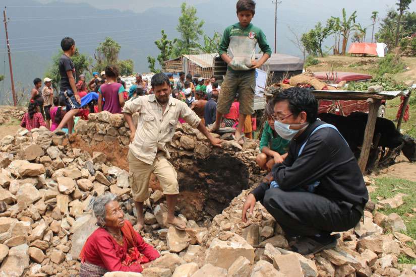 Father Ignatius Rai, vicar of Assumption Parish in Lalitpur, Nepal, chats May 9 with 85-year old Padam Kumari Magar, who had crawled out unscathed from the rubble of her stone home on Baretol Mountain after the April 25 earthquake.