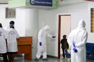 A Kenyan Port Health Services worker wearing full personal protective equipment commands a small boy, who is among nine Kenyans who were stranded in the Ebola-hit country Liberia, to return to an observation room for Ebola screening, as they arrive at Jomo Kenyatta International Airport Oct. 28 in Nairobi, Kenya.