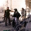 A member of the Free Syrian Army helps women as they leave a shelled building in Aleppo. The Armenian Orthodox primate of Damascus sees little hope of democracy taking hold when the Syrian civil war ends.