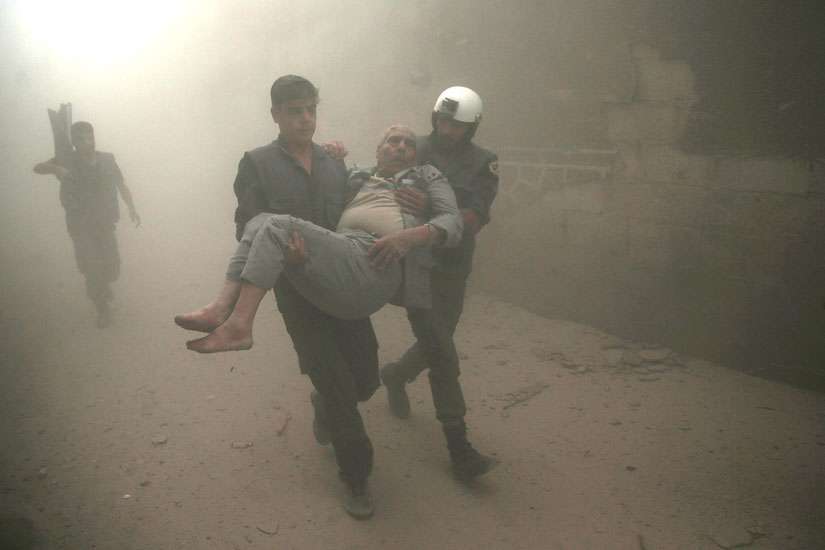 Civil defense members carry an injured man after an Oct. 12 airstrike in Damascus, Syria. In the wake of intensified attacks, Pope Francis called for an immediate cease-fire, even if temporary, so that civilians, especially children, could be rescued from the ruins.